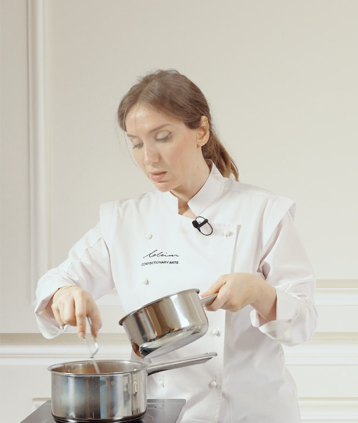 A pastry chef in a white Lalina jacket working at the stove